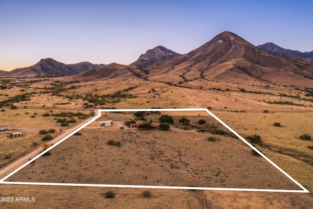 aerial view at dusk featuring a mountain view and a rural view