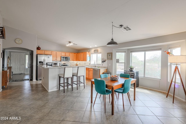 tiled dining room with a wealth of natural light, sink, and lofted ceiling