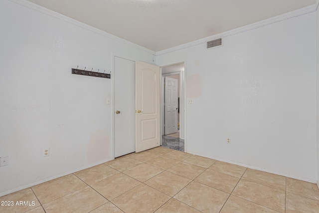 unfurnished room with light tile patterned floors and crown molding