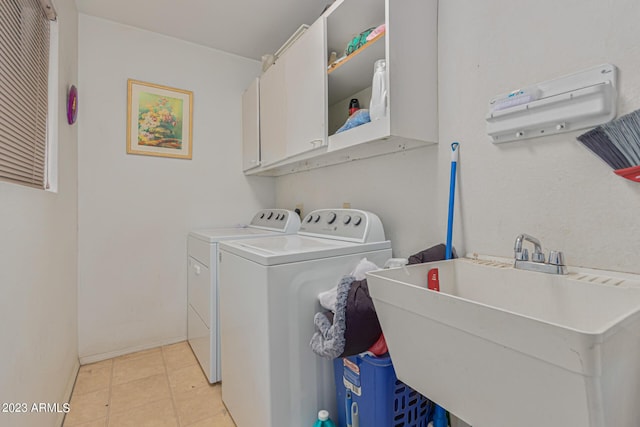 clothes washing area with sink, washer and clothes dryer, cabinets, and light tile patterned flooring