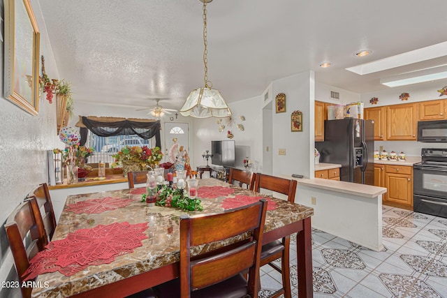 dining room featuring ceiling fan, a textured ceiling, and a skylight