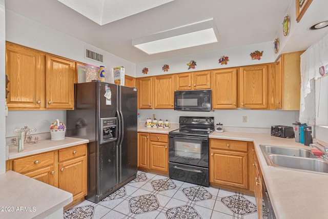 kitchen with light tile patterned floors, sink, and black appliances