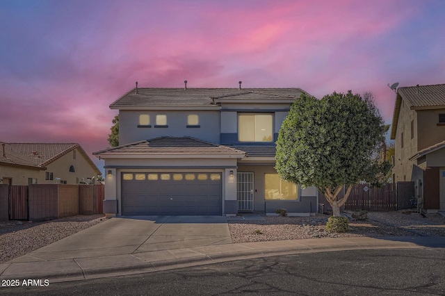 traditional-style home with concrete driveway, an attached garage, fence, and a tile roof