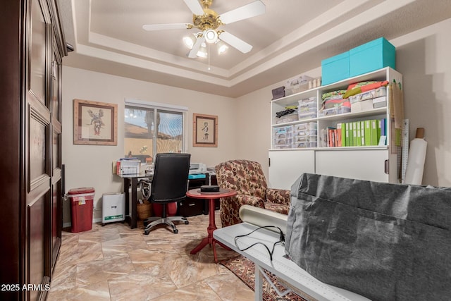 home office with ceiling fan and a tray ceiling