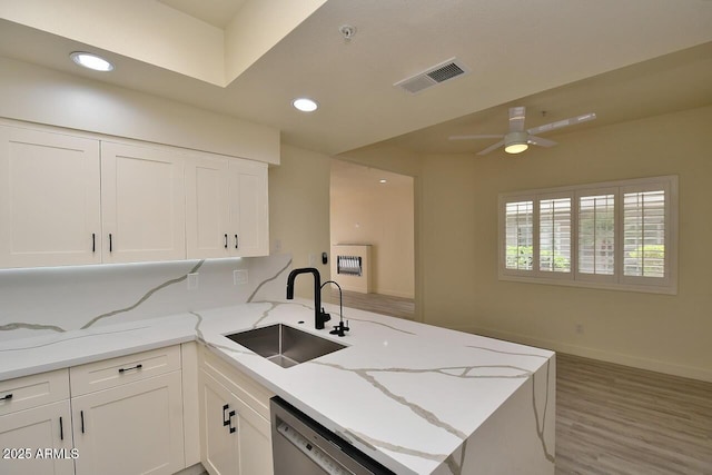 kitchen with sink, dishwasher, light stone counters, white cabinets, and kitchen peninsula