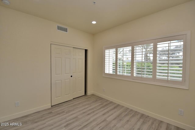 unfurnished bedroom with light hardwood / wood-style flooring and a closet