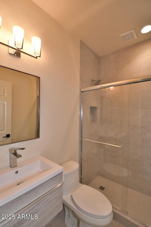 bathroom with a shower with door, vanity, and toilet