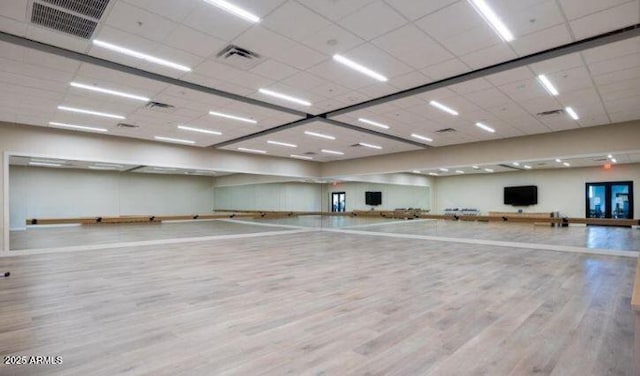 workout room with a drop ceiling and light hardwood / wood-style floors