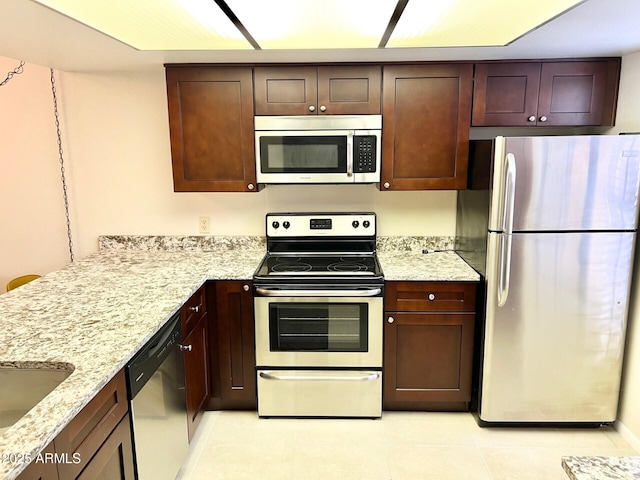 kitchen with appliances with stainless steel finishes, light tile patterned floors, light stone counters, and sink