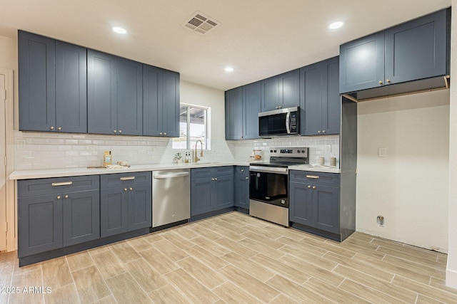 kitchen featuring visible vents, a sink, tasteful backsplash, stainless steel appliances, and light countertops