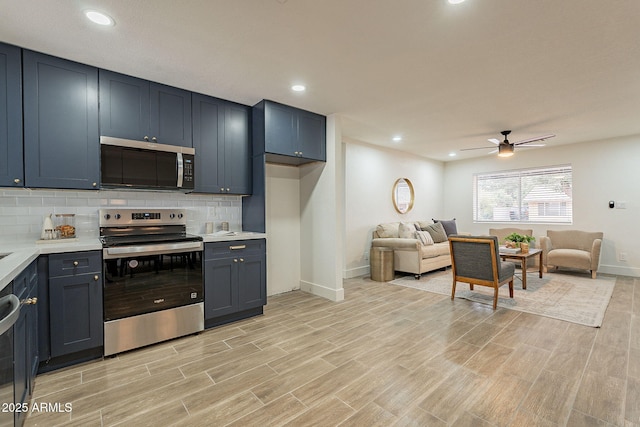 kitchen with wood finish floors, stainless steel appliances, light countertops, decorative backsplash, and ceiling fan