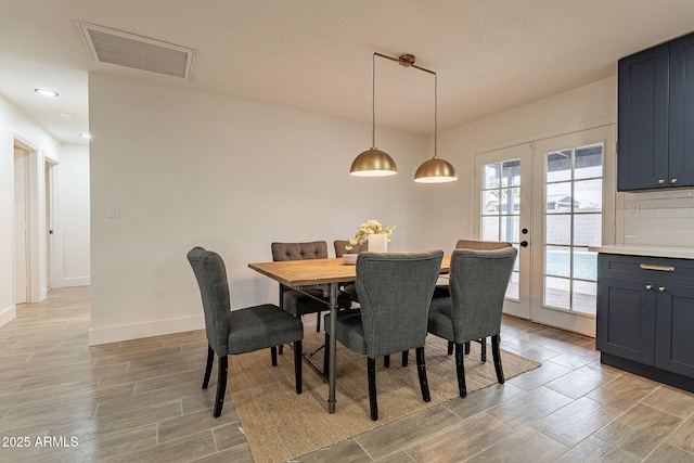 dining room featuring wood finish floors, french doors, visible vents, and baseboards