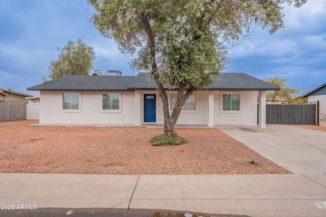 ranch-style house with stucco siding, concrete driveway, roof with shingles, and fence