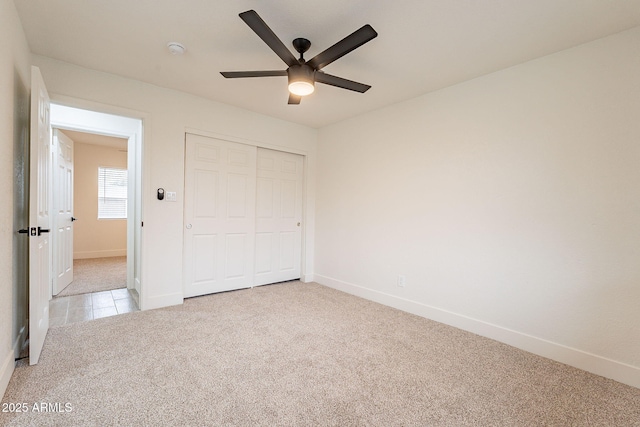 unfurnished bedroom featuring a closet, baseboards, carpet, and a ceiling fan