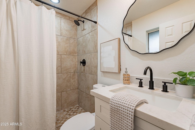 bathroom featuring tiled shower, toilet, and vanity