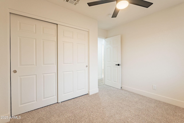 unfurnished bedroom featuring visible vents, a closet, baseboards, light colored carpet, and ceiling fan