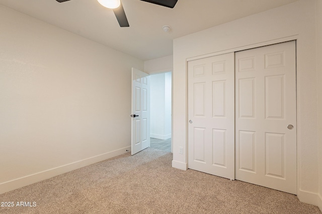 unfurnished bedroom featuring a closet, light colored carpet, a ceiling fan, and baseboards