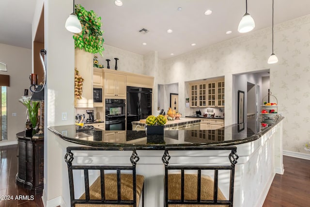 kitchen with kitchen peninsula, a breakfast bar, black appliances, pendant lighting, and dark hardwood / wood-style floors