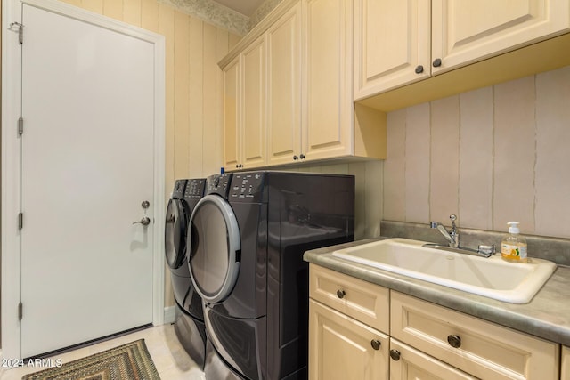 clothes washing area featuring washer and clothes dryer, cabinets, and sink