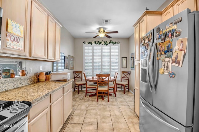 kitchen with ceiling fan, light tile patterned floors, light brown cabinetry, appliances with stainless steel finishes, and light stone counters