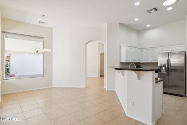 kitchen featuring kitchen peninsula, stainless steel refrigerator with ice dispenser, decorative light fixtures, a chandelier, and white cabinetry