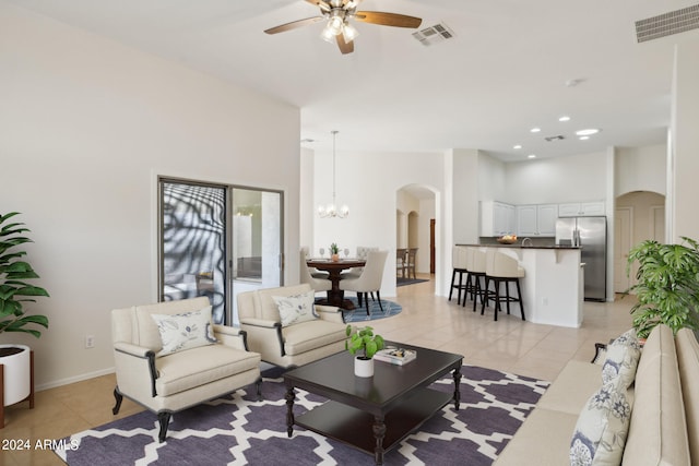 tiled living room featuring ceiling fan with notable chandelier