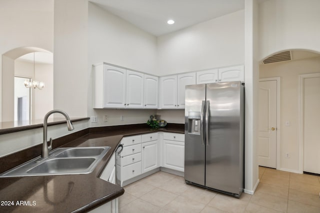 kitchen with white cabinets, stainless steel fridge, a towering ceiling, and sink