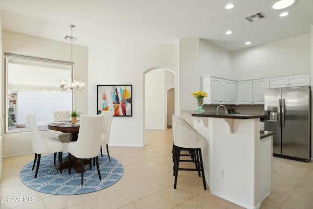 15016 W Monterey Way, Goodyear, AZ 85395 - kitchen featuring a breakfast bar, dark countertops, stainless steel refrigerator with ice dispenser, white cabinetry, and arched walkways