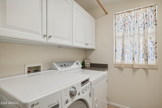 clothes washing area featuring washing machine and dryer and cabinets