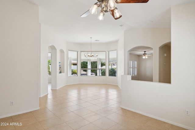 tiled empty room featuring ceiling fan with notable chandelier