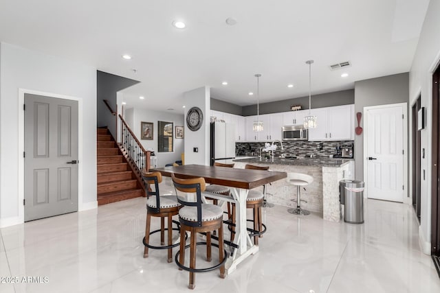 kitchen with a center island, tasteful backsplash, white cabinets, decorative light fixtures, and white fridge