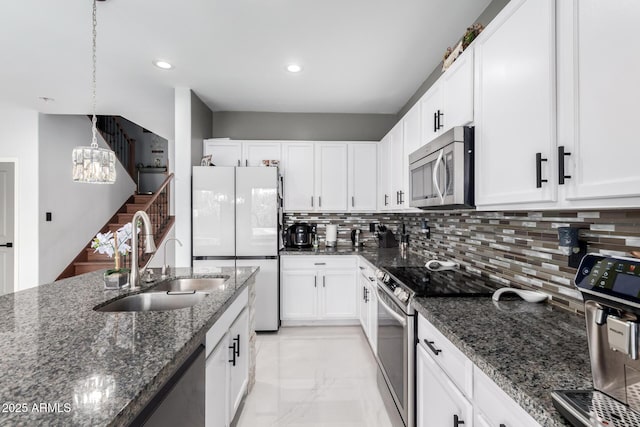 kitchen with white cabinetry, appliances with stainless steel finishes, sink, and dark stone countertops