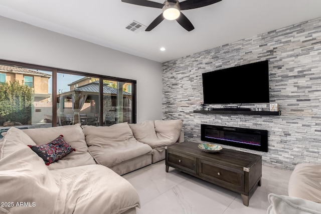 living room with a stone fireplace and ceiling fan