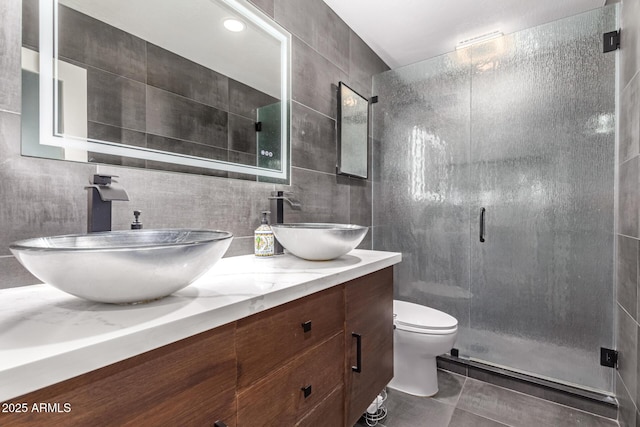 bathroom with tile walls, vanity, a shower with shower door, and toilet