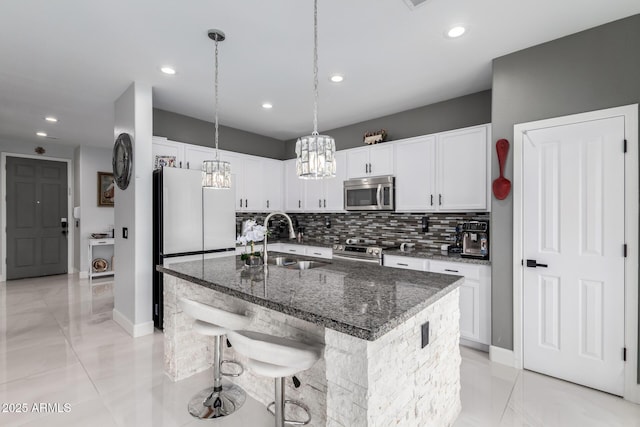 kitchen featuring appliances with stainless steel finishes, a breakfast bar, white cabinetry, sink, and a center island with sink