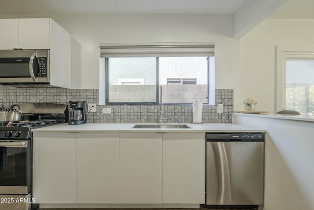kitchen featuring stainless steel appliances, sink, white cabinets, and backsplash
