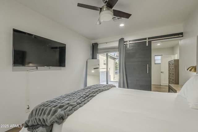 bedroom with a barn door, access to outside, and ceiling fan