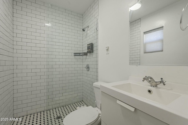 bathroom featuring vanity, a tile shower, and toilet