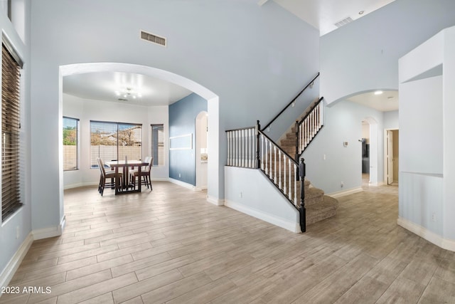 interior space with a towering ceiling and light hardwood / wood-style floors