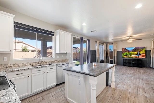 kitchen with light hardwood / wood-style flooring, white cabinets, plenty of natural light, and stainless steel dishwasher