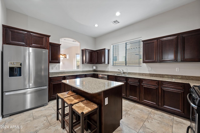 kitchen with stainless steel appliances, a sink, visible vents, a center island, and a kitchen bar