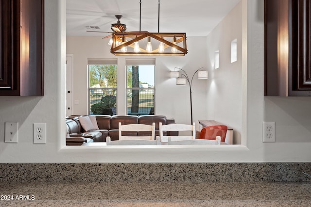 kitchen with light stone countertops, dark brown cabinetry, visible vents, and open floor plan