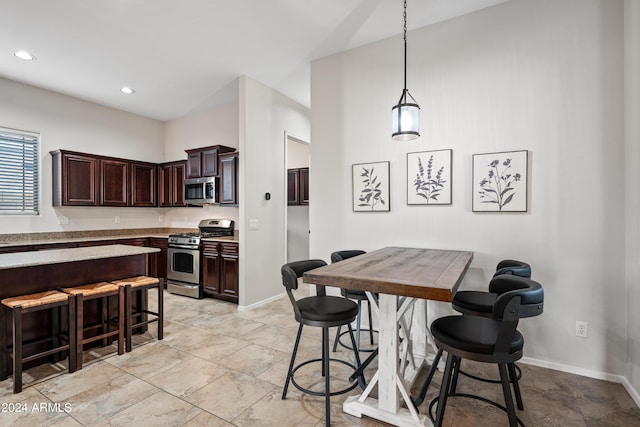 kitchen with dark brown cabinetry, baseboards, a kitchen breakfast bar, stainless steel appliances, and pendant lighting