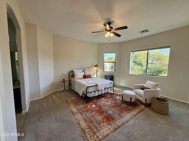 carpeted bedroom with ceiling fan, baseboards, visible vents, and arched walkways