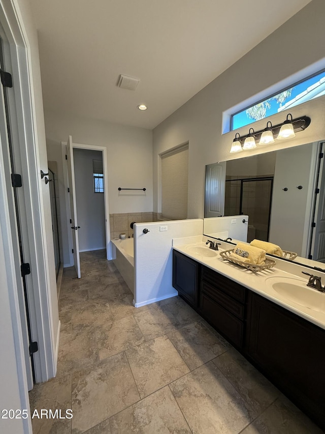 bathroom with a stall shower, double vanity, a sink, and a bath