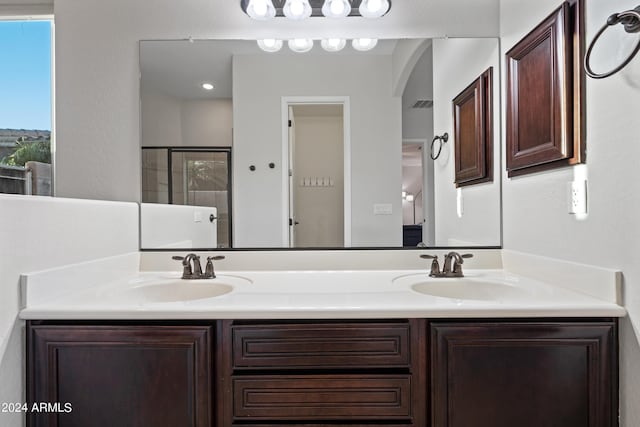 bathroom featuring an enclosed shower, a sink, and double vanity