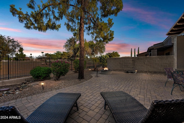 patio terrace at dusk featuring an outdoor fire pit and a fenced backyard