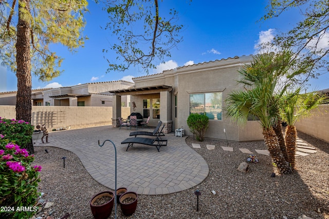 back of property featuring a tile roof, a fenced backyard, a patio, and stucco siding