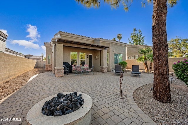 rear view of property featuring a fenced backyard, a patio area, a fire pit, and stucco siding