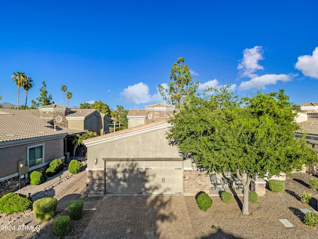 view of front of house with stone siding, decorative driveway, an attached garage, and stucco siding